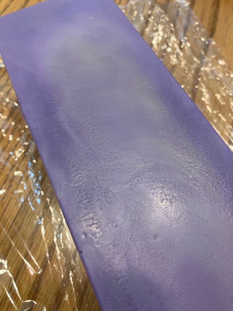 Smooth botton of purple soap with a trace of off-white swirl showing.