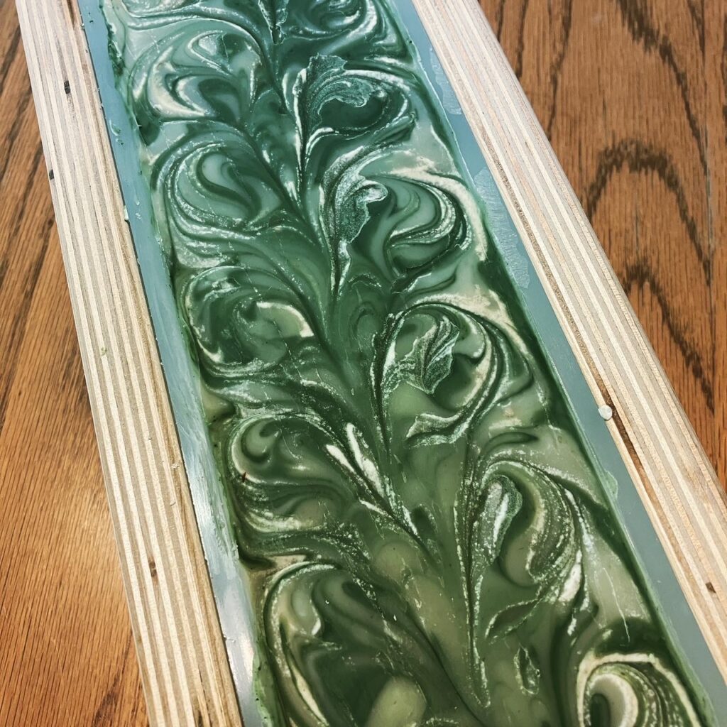 Green and white swirled soap in a wooden mold.